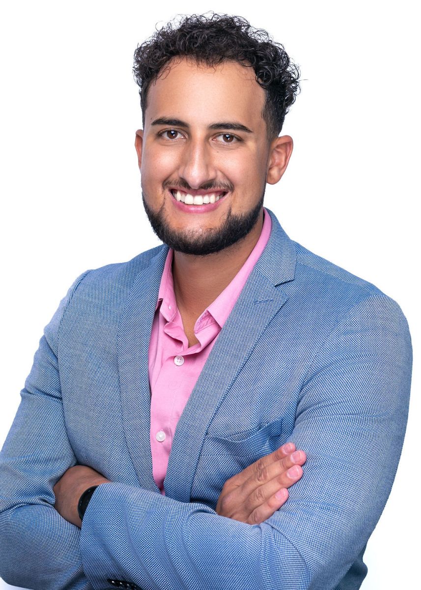 Sabastian Hague, Security Blue Team's Director of Content and Training. In his headshot, he is wearing a pale blue suit and pink shirt, with his arms crossed and a professional but approachable smile. 